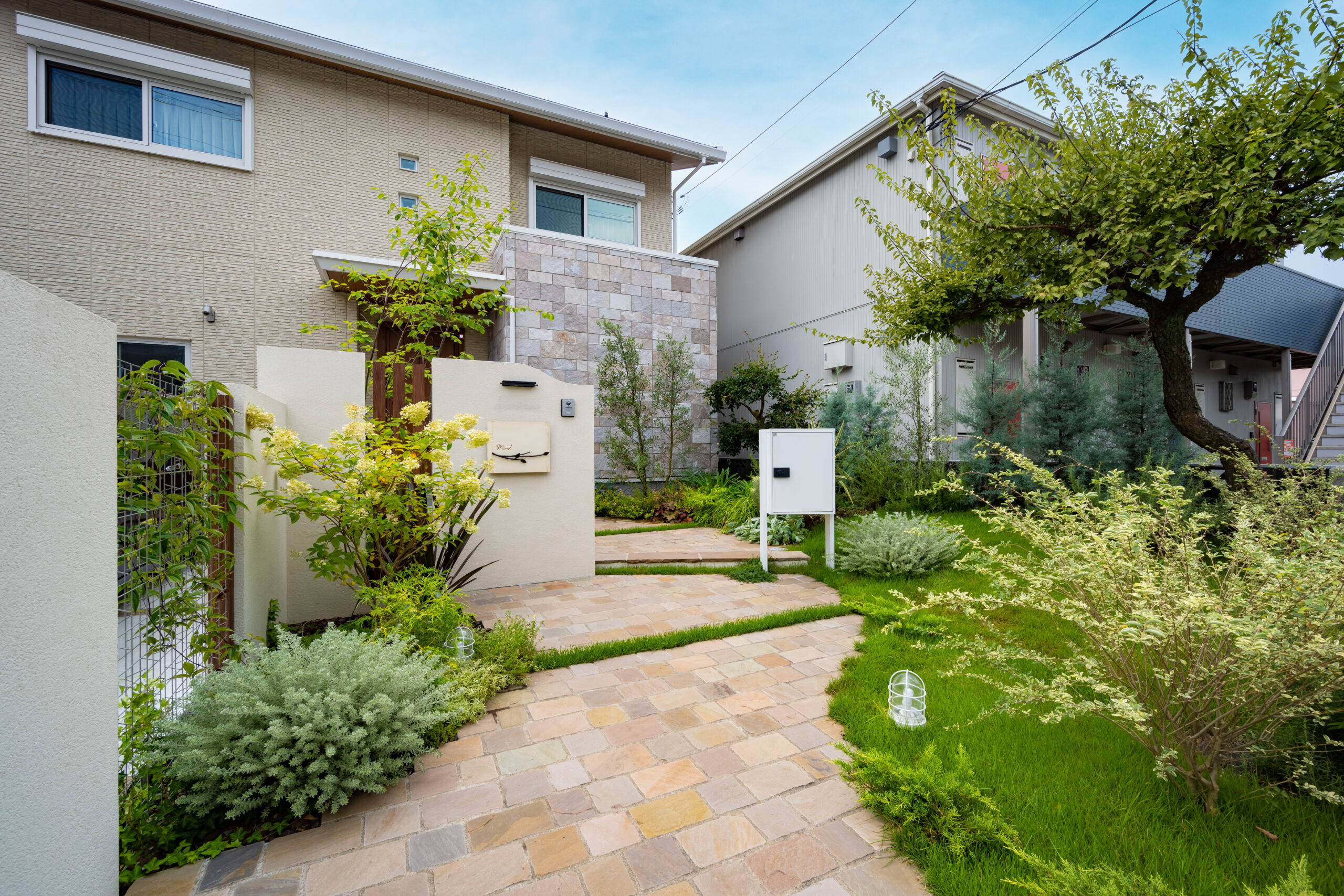 自然に囲まれた曲線アプローチが映える新築外構